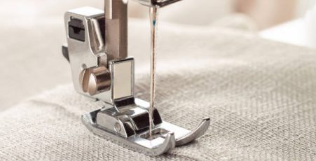 Modern sewing machine presser foot with linen fabric and thread, closeup, copy space. Sewing process clothes, curtains, upholstery. Business, hobby, handmade, zero waste, recycling, repair concept
